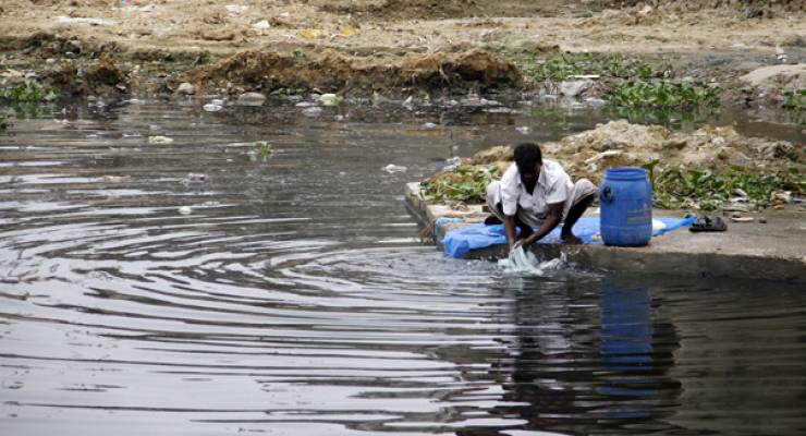 Mann wäscht Kleidung in verschmutztem Gewässer; Foto: Pijush Saha. Shiykh Seraj (flickr)